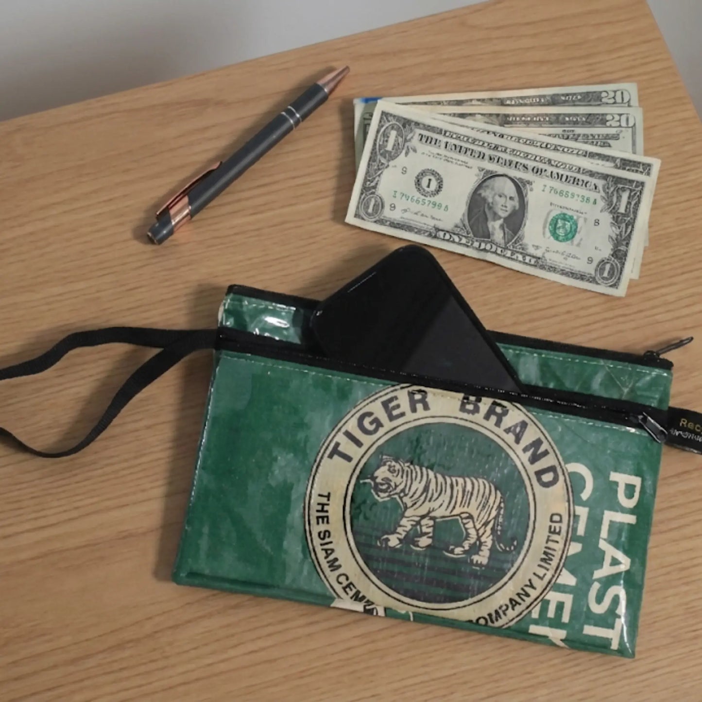 Green Tiger Brand wristlet on a wooden surface with dollar bills and a pen. styles a ShopTukTuk.com