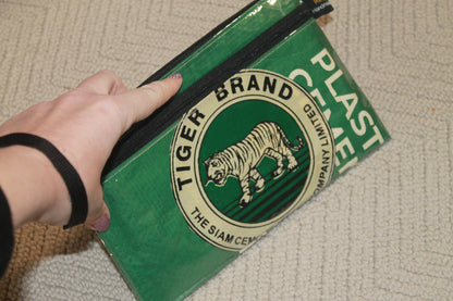 Green bag with Tiger Brand logo held by a hand on a textured surface from Tuk Tuk Trading