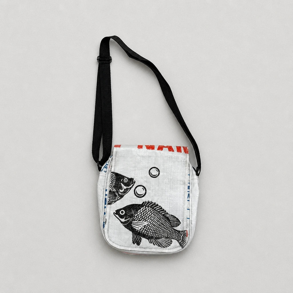 Upcycled crossbody bag with black and white fish design on a gray background